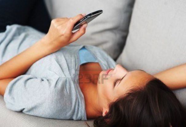 pretty-woman-concentrating-on-smart-phone-while_lying-on-sofa